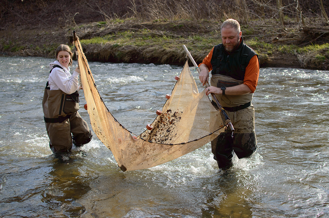 Maddie Miller, a photo student at Bellaire High School, and Professor Loughman use a net to collect aquatic wildlife in McMahon Creek in Ohio. (Photograph by Dane DāAquila)